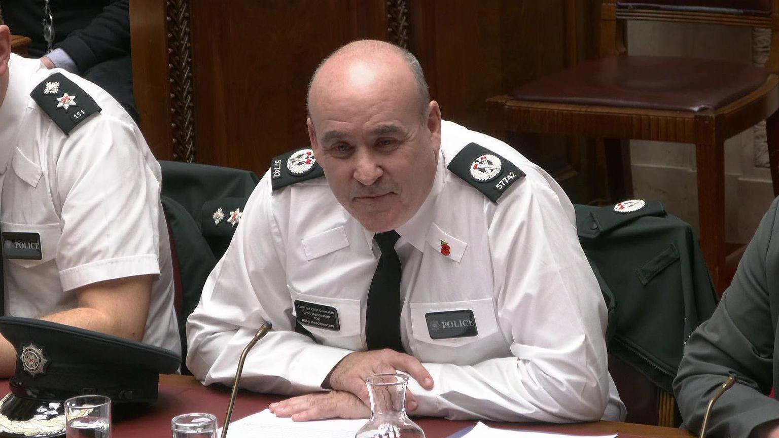 Assistant Chief Constable Ryan Henderson sitting at a desk in his PSNI officer uniform.