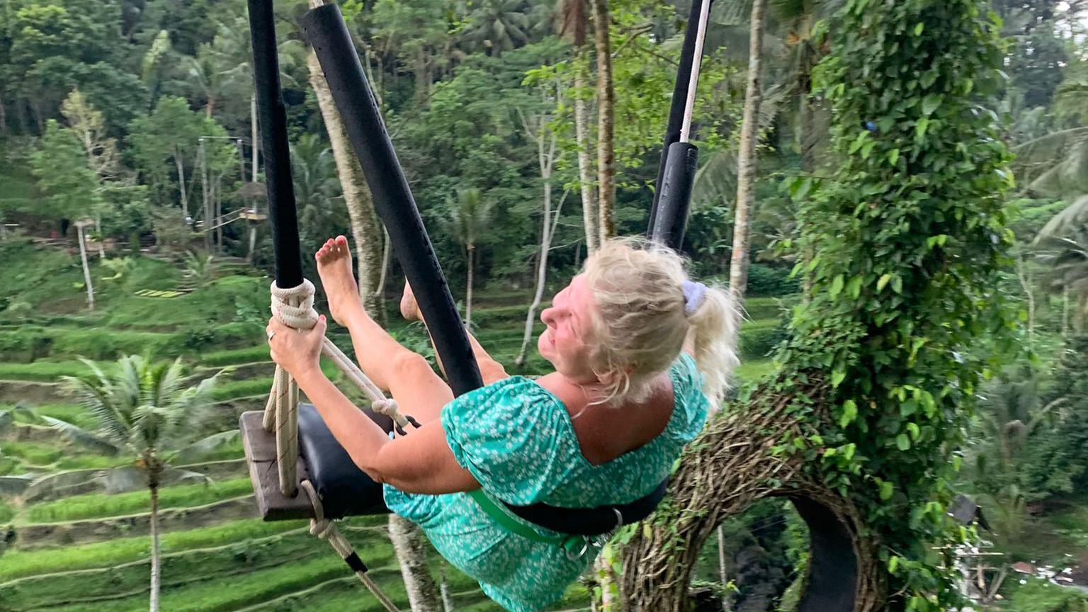 Nicky Maidment wearing a green dress swinging on a tree swing