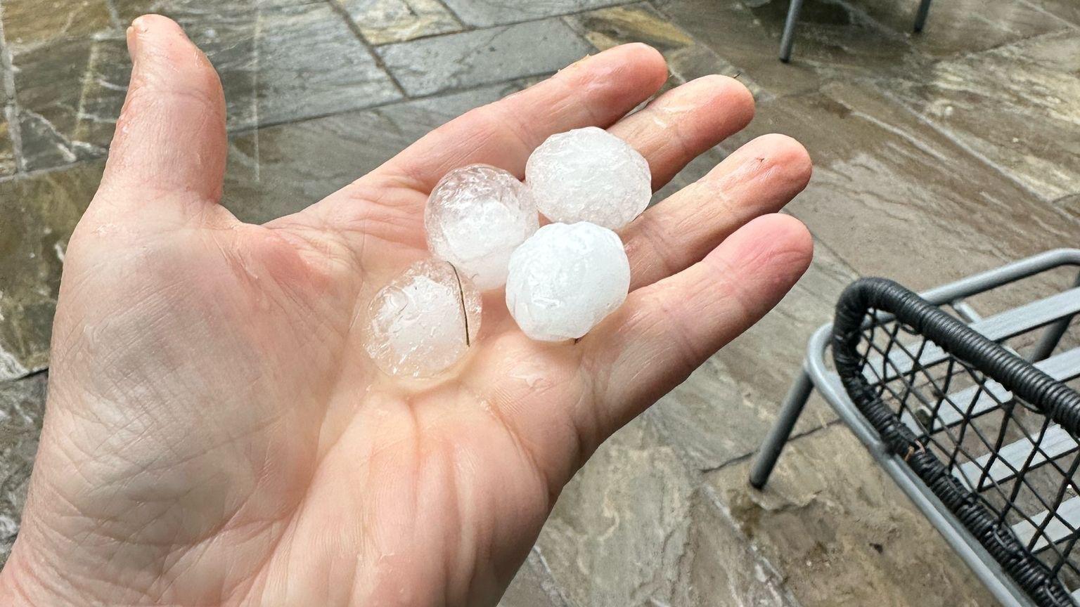 Hand holding four hailstones the size of ice cubes