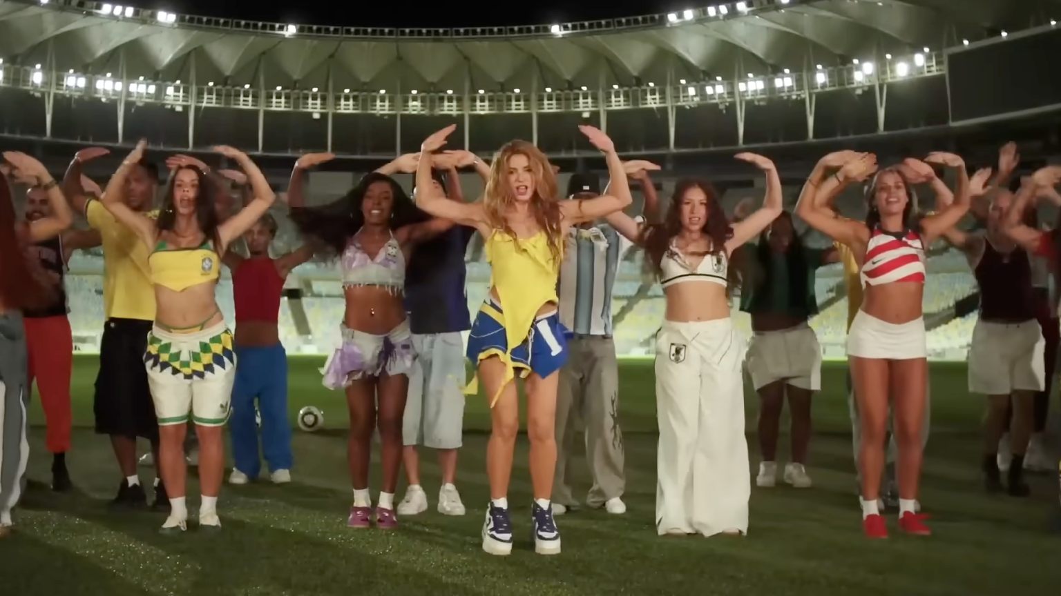 Shakira and dancers performing in a football stadium.