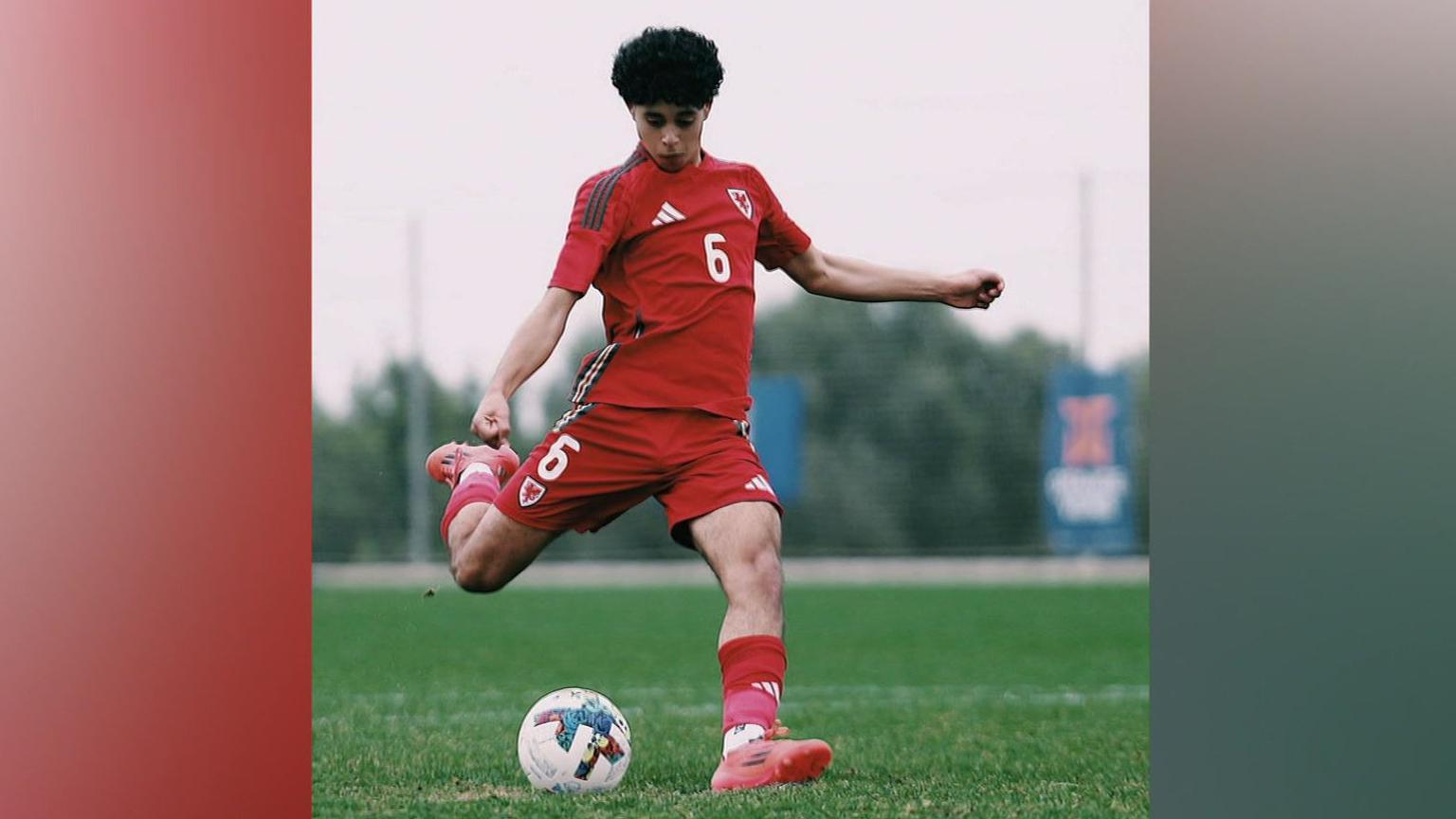 Enzo Romano mewn cit Cymru yn cicio pel