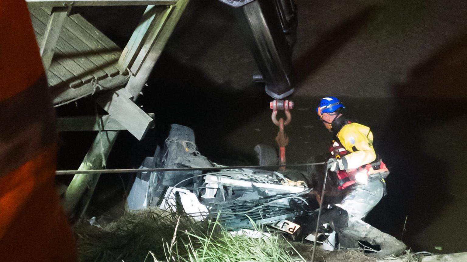 An emergency service team member is winched down to help recover the vehicle from the mud