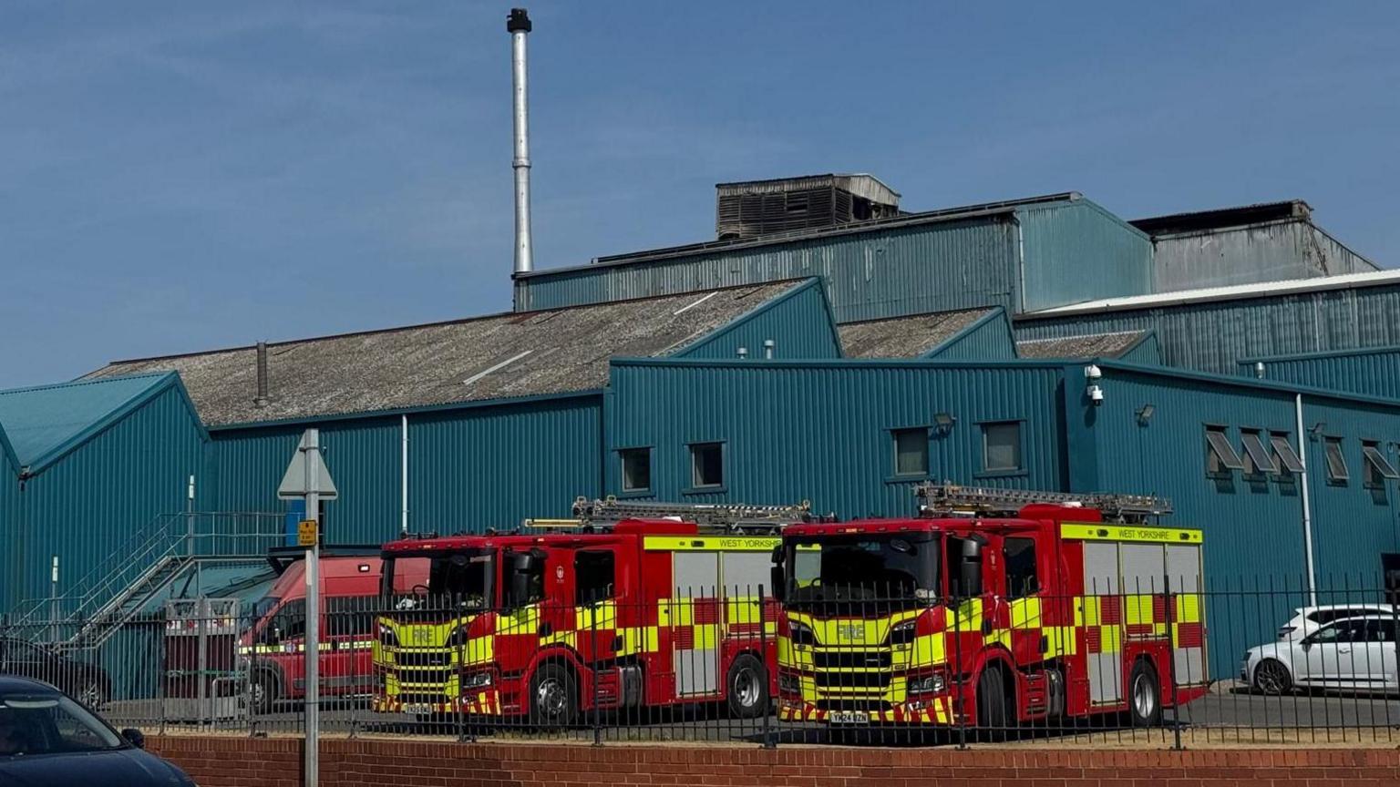 Two fire engines and a fire service vehicle outside a factory building.
