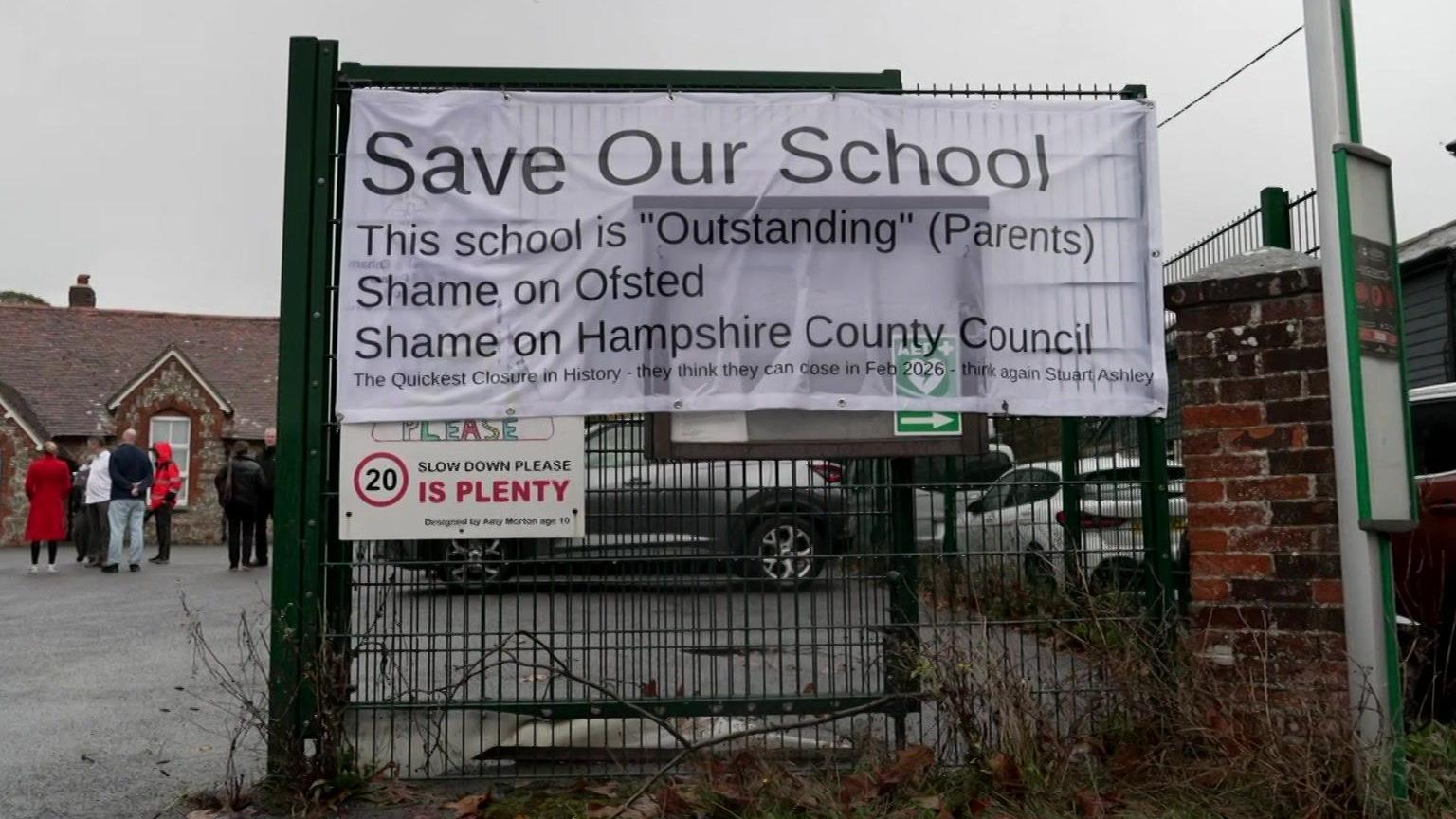 A banner on the school gates reads "Save our school" and says "shame on" Ofsted and the council.