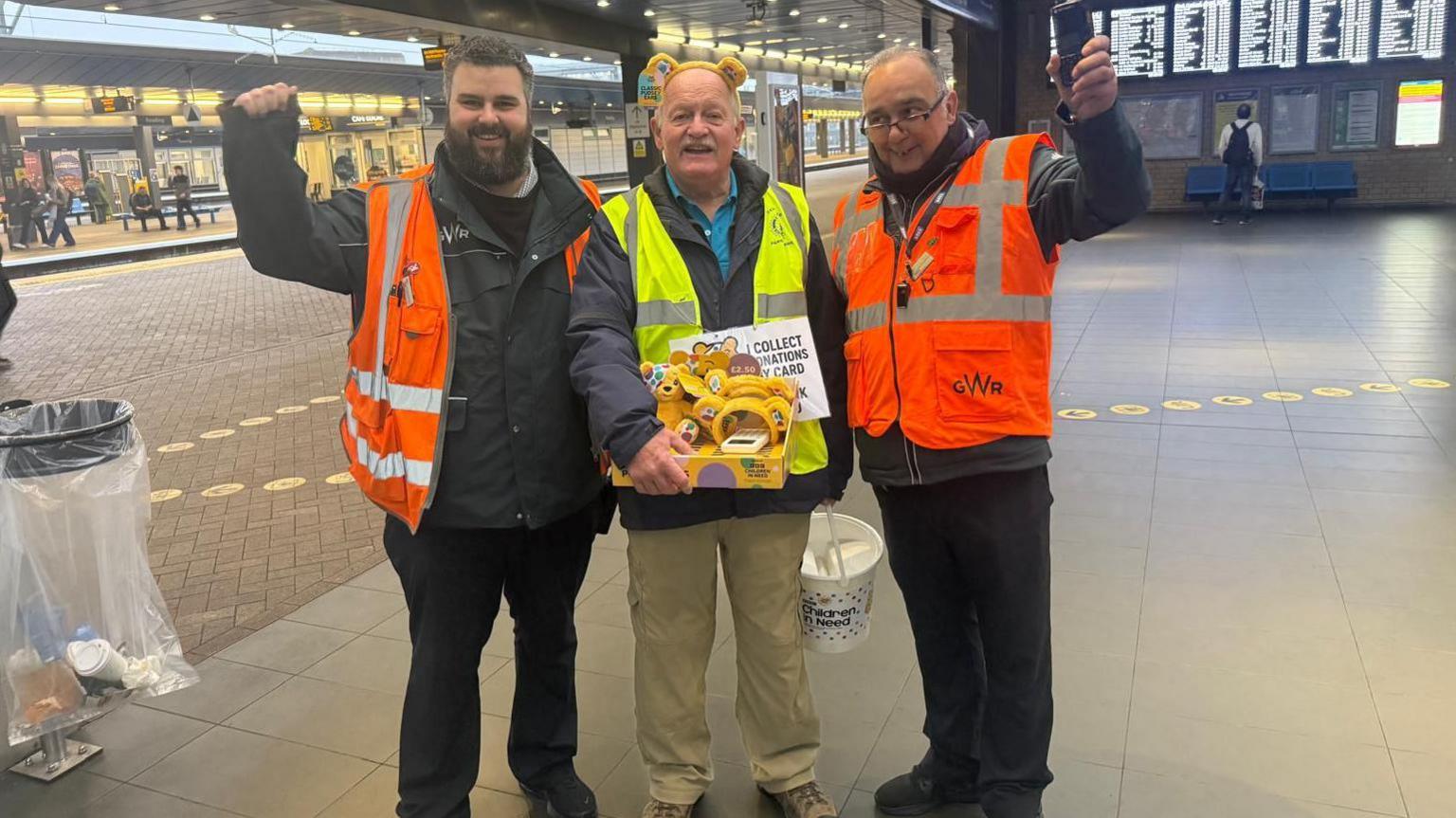 A Rotary Club member with CIN merchandise and a collecting bucket, with two GWR staff