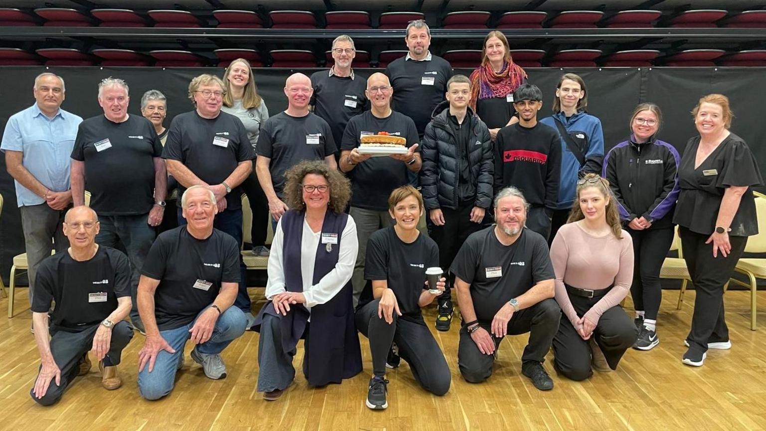 20 volunteers pose in a community hall