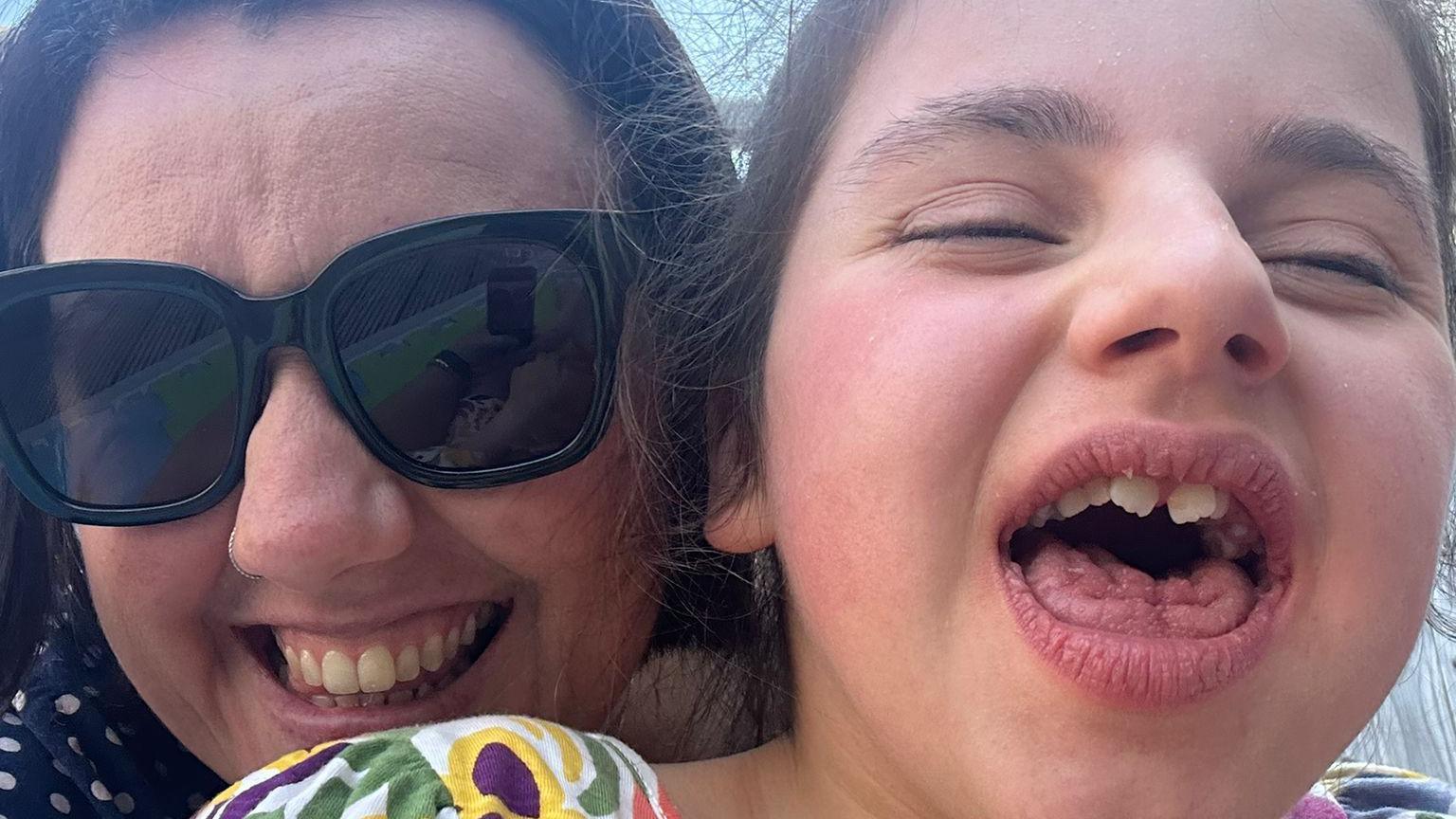 A close up of Kirsty with Edith smiling at the camera. Kirsty is wearing shades.