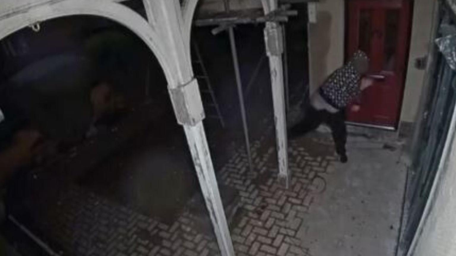 Doorbell camera footage of a man in black and white clothing throwing a rock at a window