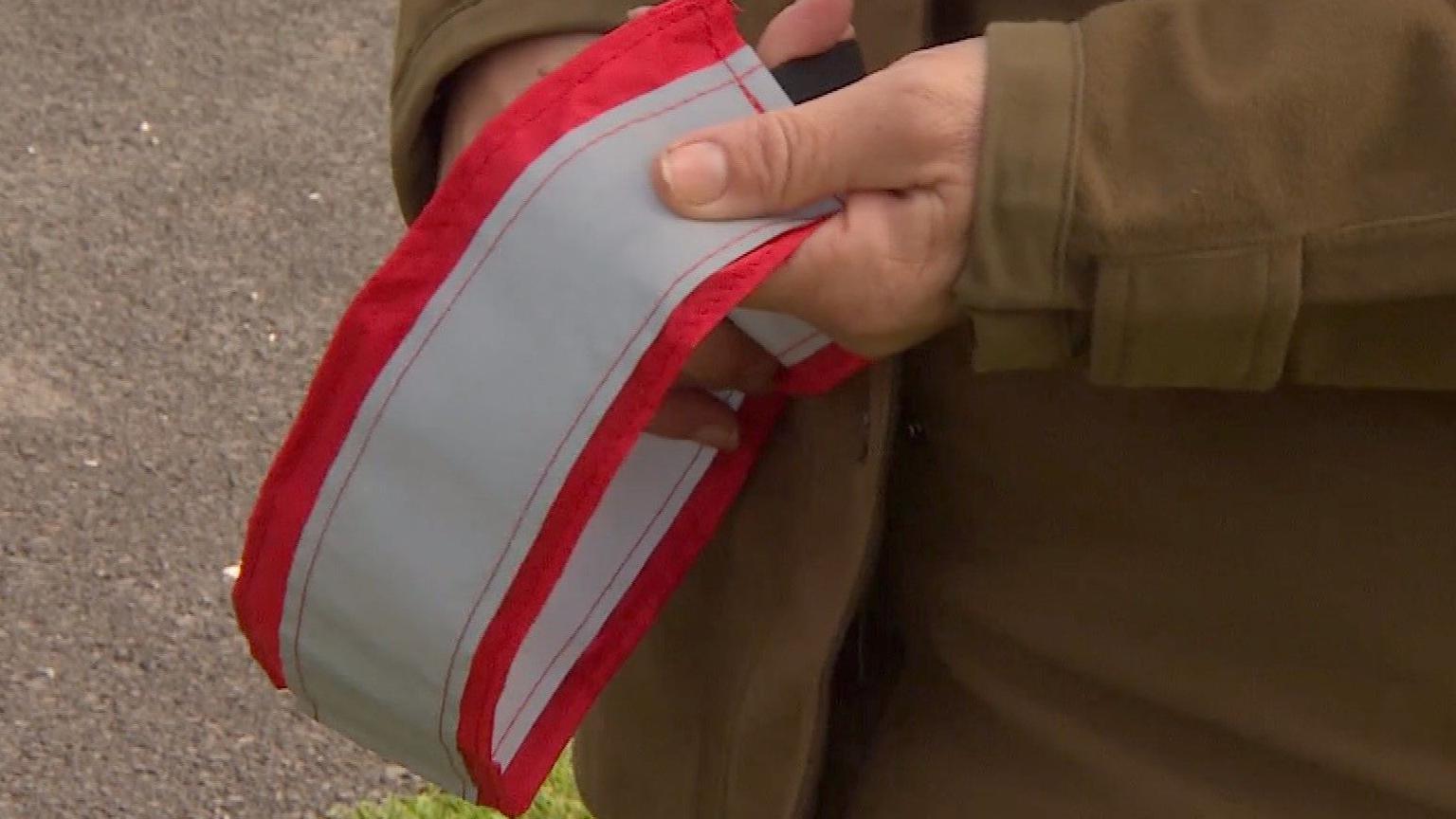 A close up silver and red reflective collar being held by a woman