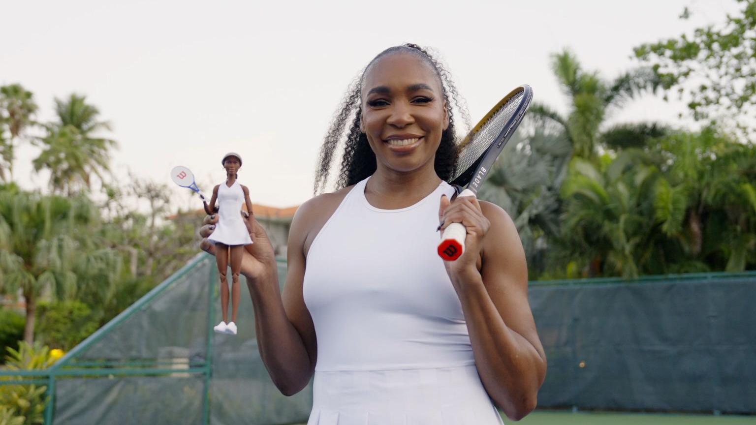 Tennis player Venus Williams stands on court holding her own Barbie doll