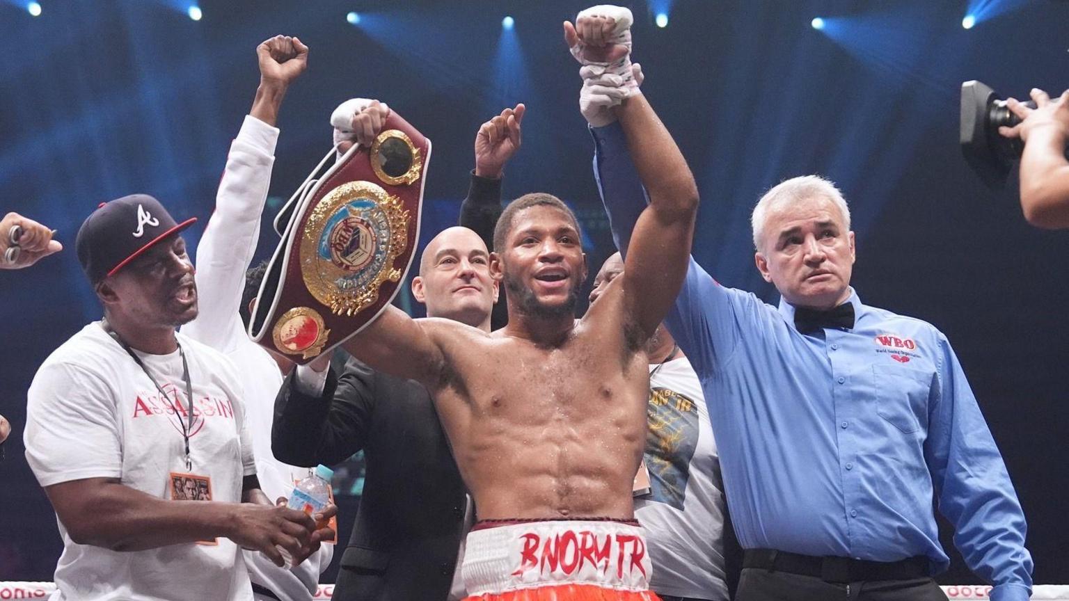 Brian Norman Jr smiles and holds up his WBO title as the referee lifts his hand