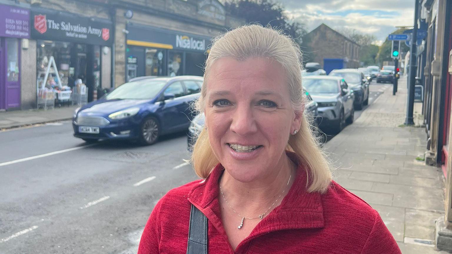 Kathryn, who is wearing a red top, smiles in Birstall.