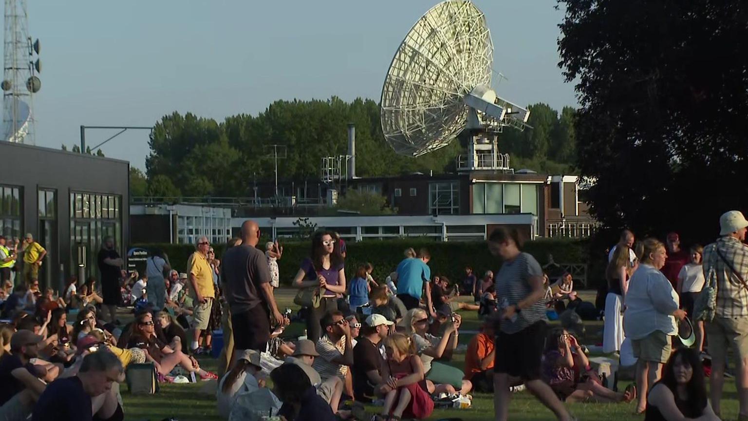 People view the eclipse with the dish of Jodrell Bank radio telescope in the background.