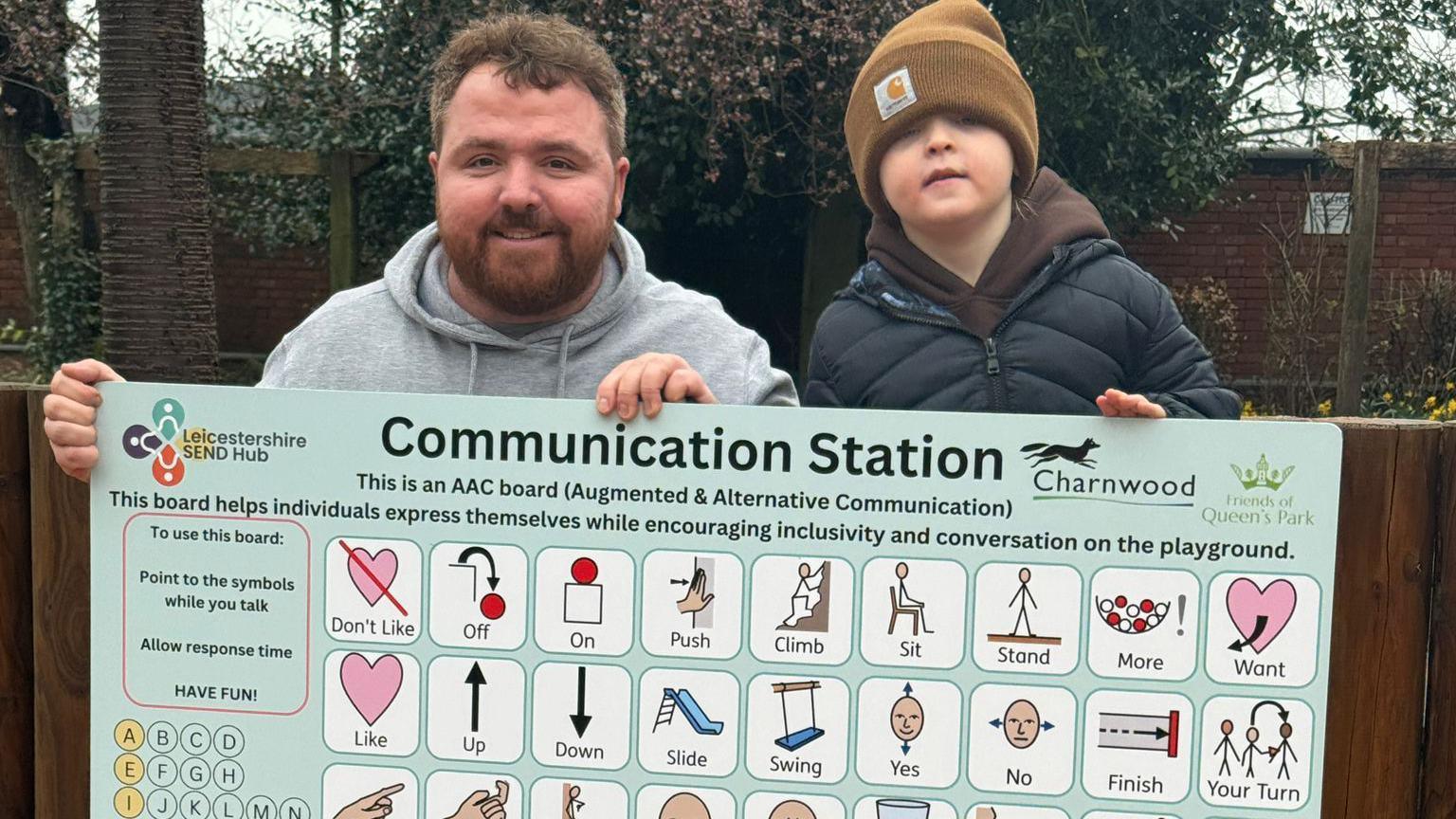 Robert Martin and his seven-year-old son, standing behind a communication board