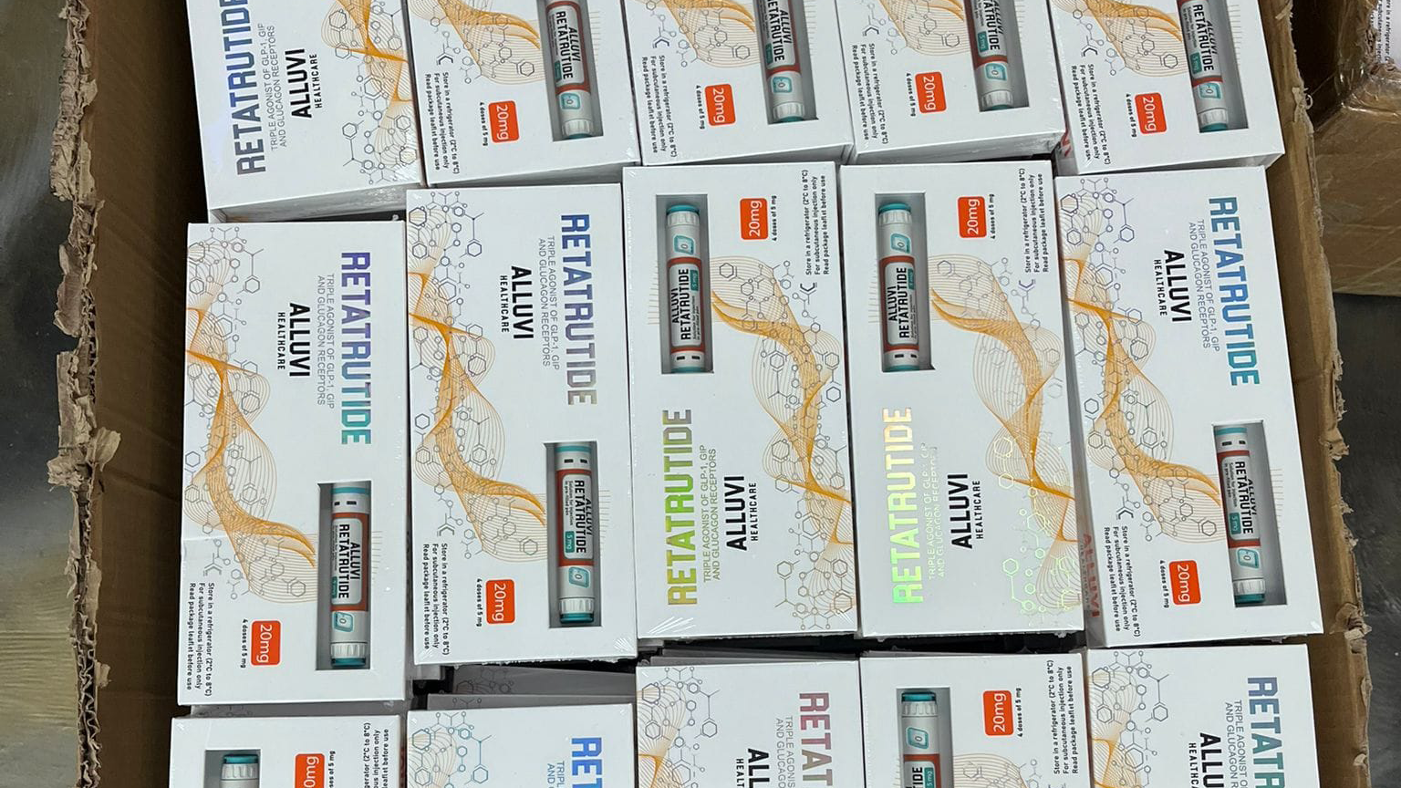 Boxes of fake weight loss medication, in boxes, with a weight loss pen in them. The boxes are white with writing on them.