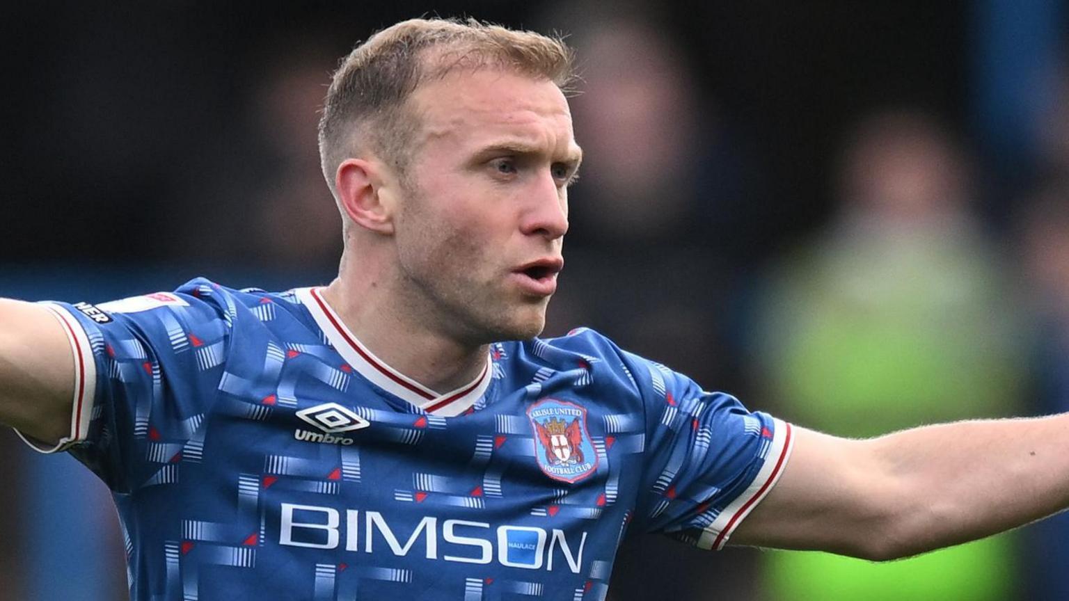 Dylan McGeouch playing for Carlisle at Brunton Park with arms outstretched