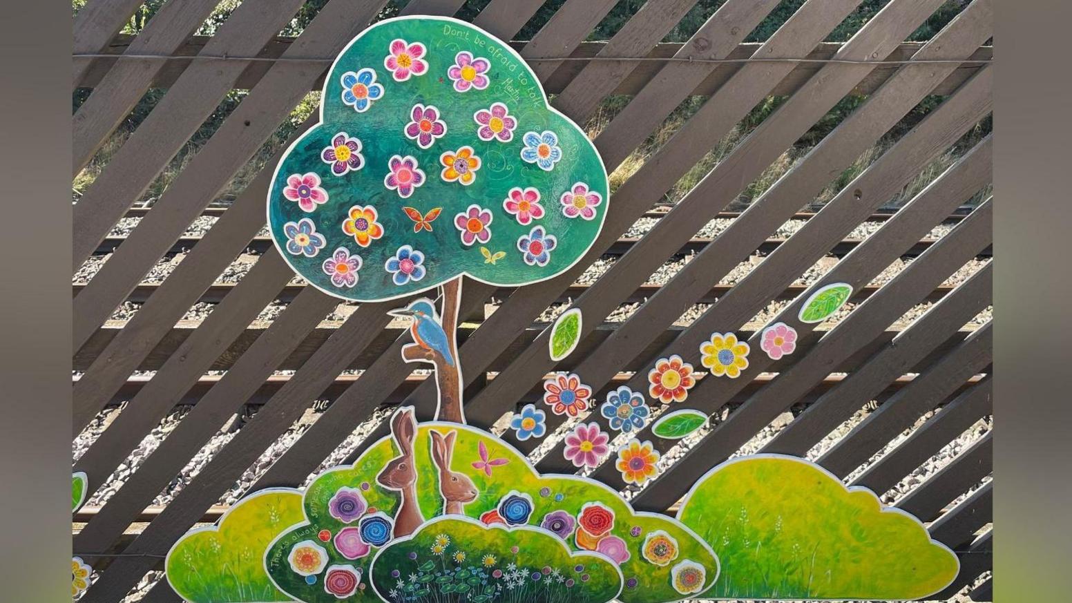 A painting of a tree and a bush with rabbits in on a fence