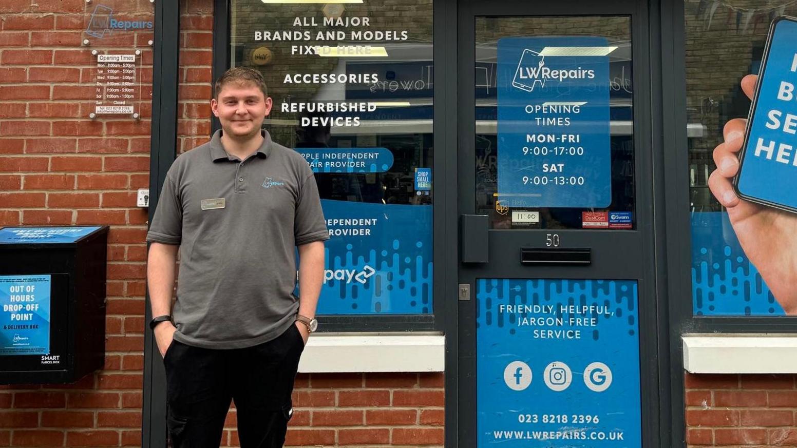 Lewis Watson standing outside his computer repair shop with blue notices on the door and windows