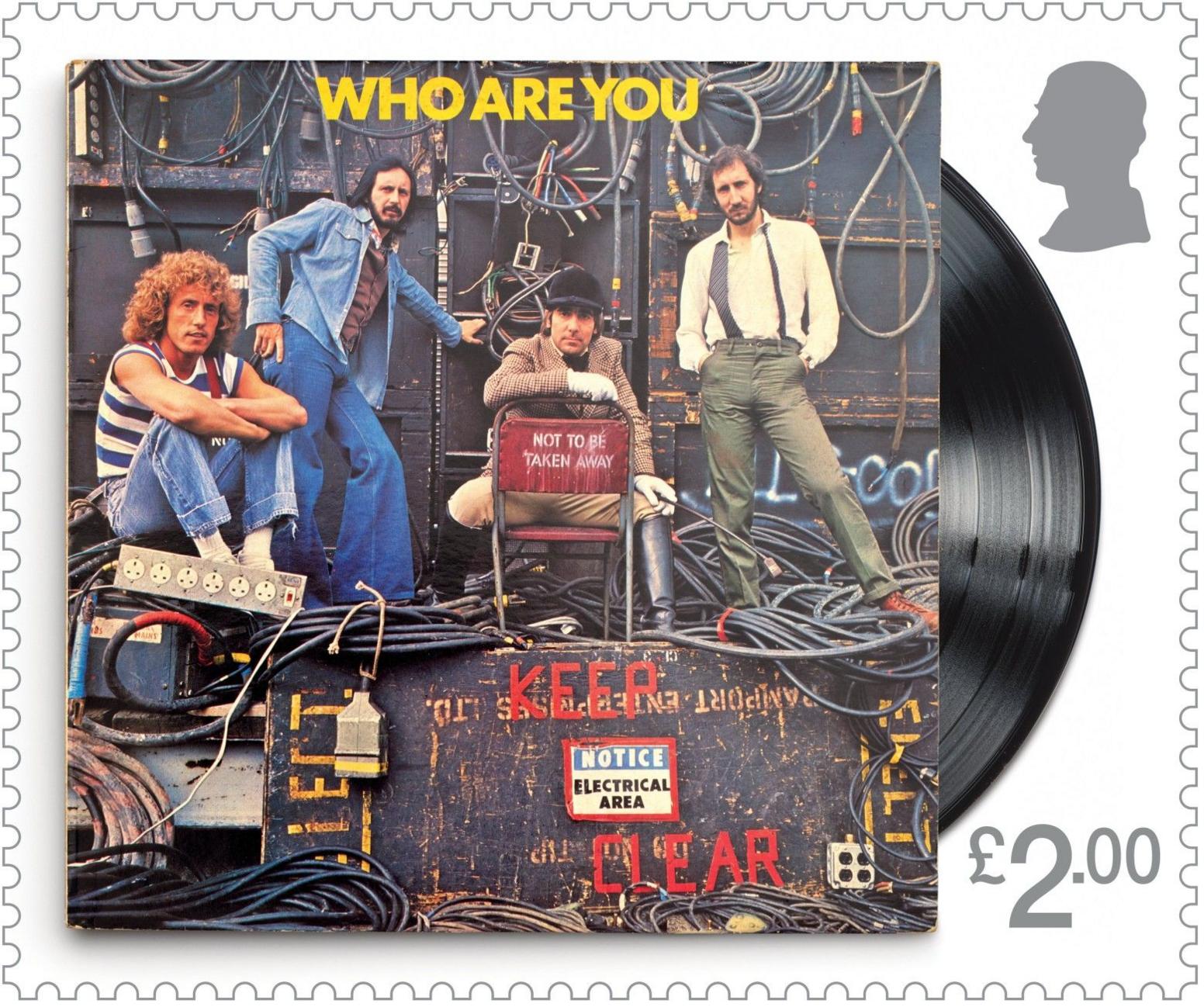 This stamp features the band surrounded by electrical equipment with a red keep clear sign around a notice saying electrical area. It has a grey £2 price tag and part of a vinyl is visible behind it.