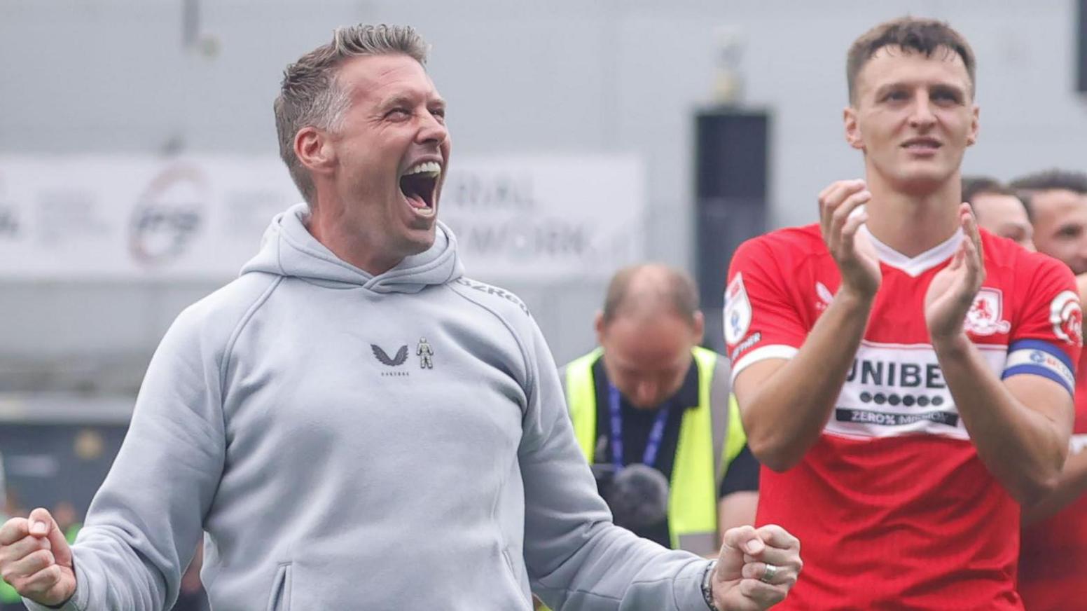 Rob Edwards, with fists clenched, celebrating in front of Boro fans after winning at Millwall, with captain Dael Fry just behind him 