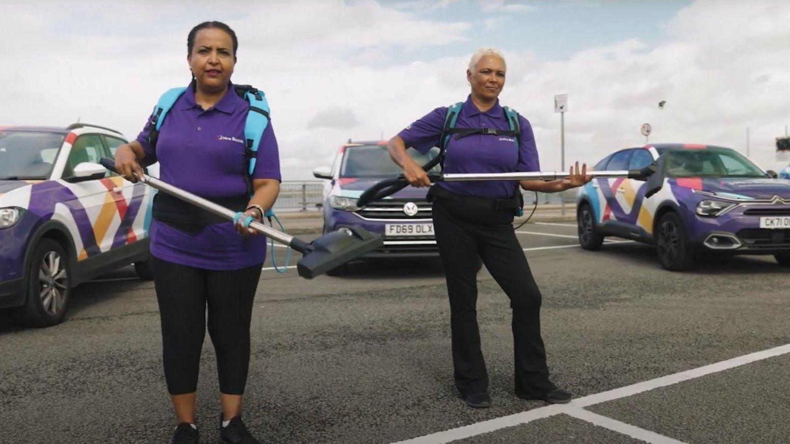 Cleaning staff from Mrs Buckét posing with their backpack vacuum cleaners and company branded vehicles.