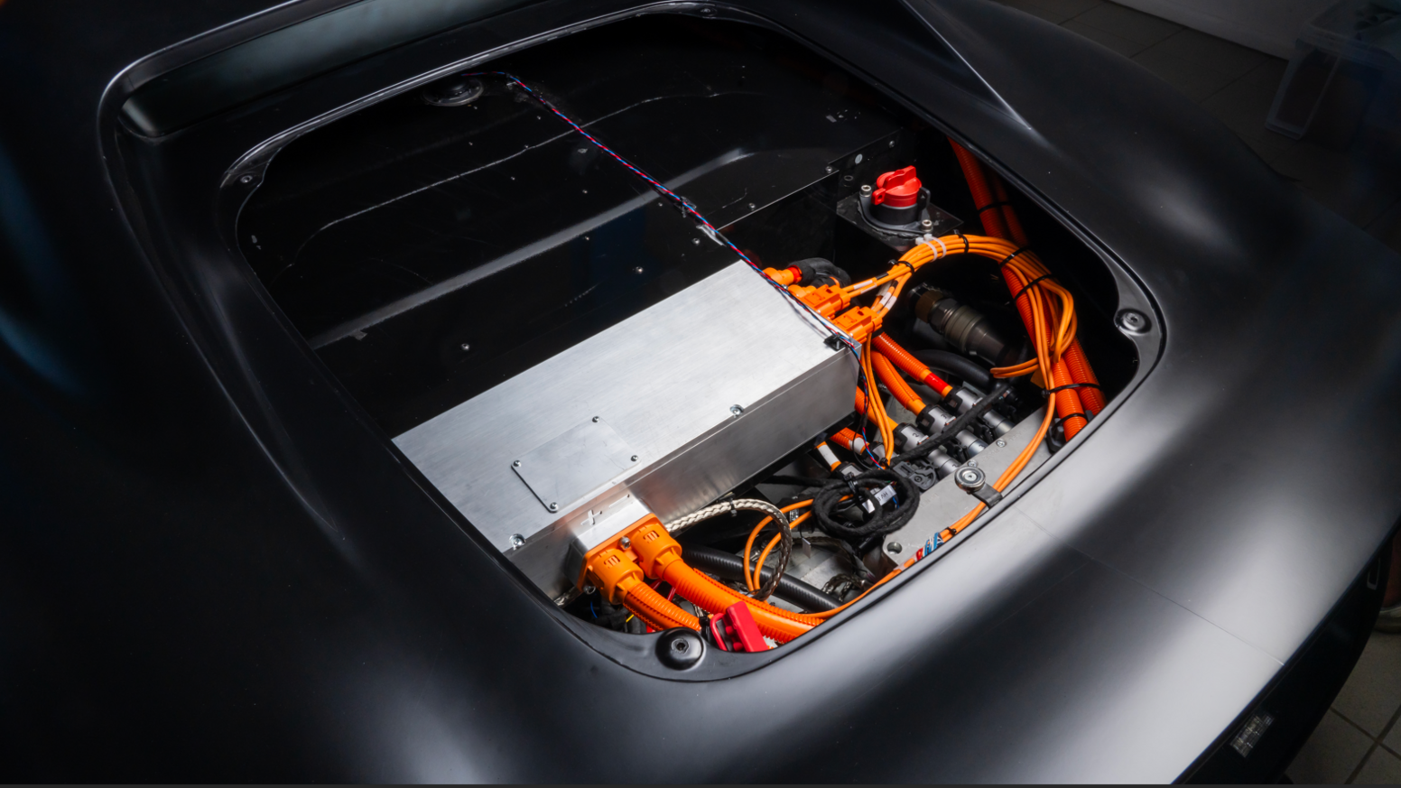 The inside of a sports car - lots of wires and cables neatly organised around a large metallic rectangle