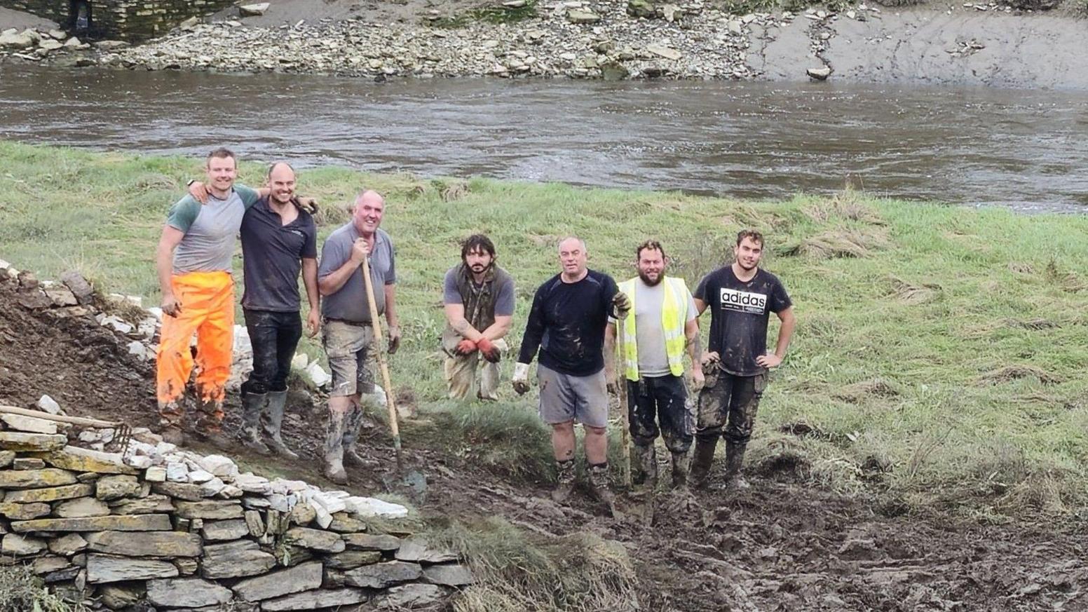 Five men working on a stone island on a river bed when the tide is out