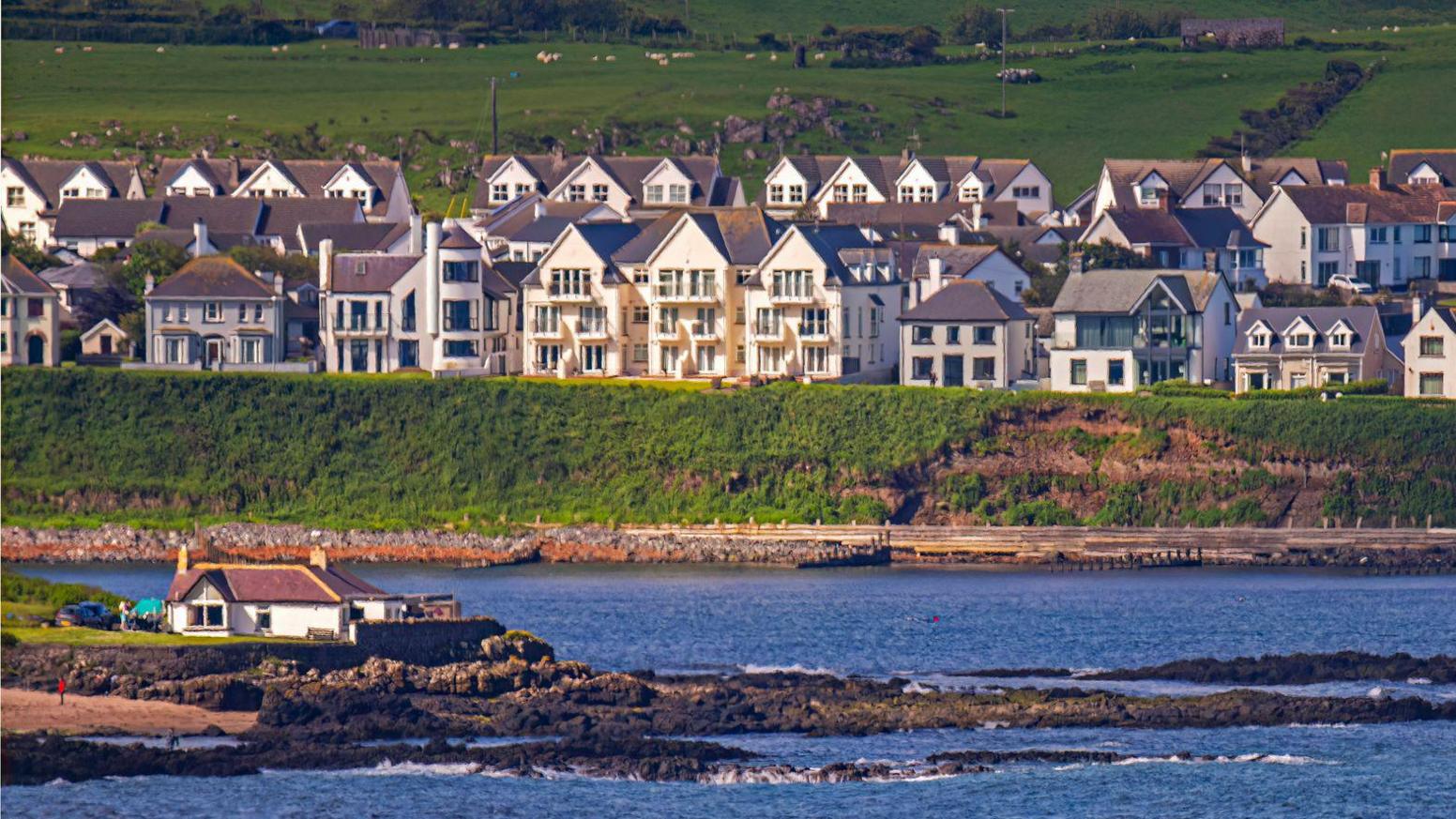 A view of Portballintrae, showing the coastline and houses on the bank