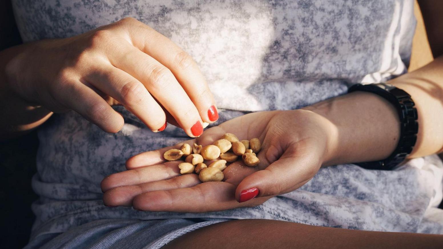 Woman eating a pile of peanuts from her hands