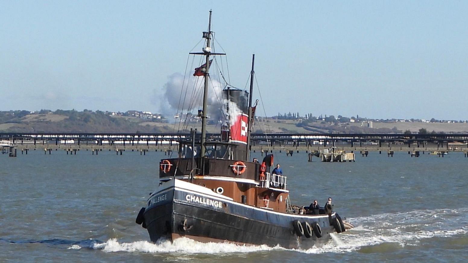 A steam tugboat named Challenge is sailing on a river.