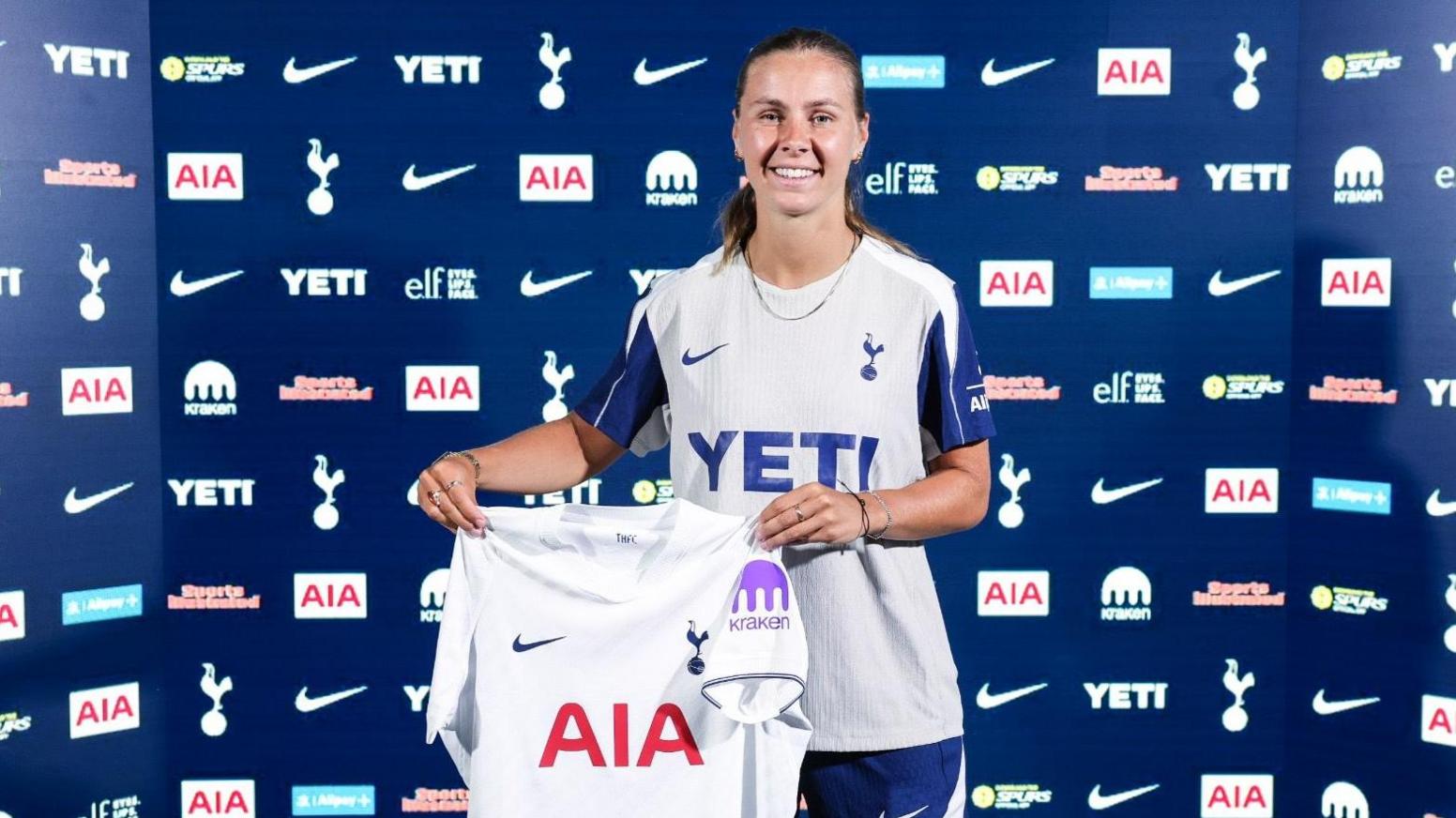 Victoria Pelova faces the camera while holding a Tottenham shirt
