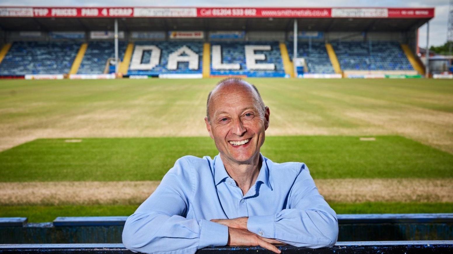 Paul Waugh smiles as he poses for a photo at Rochdale's football stadium