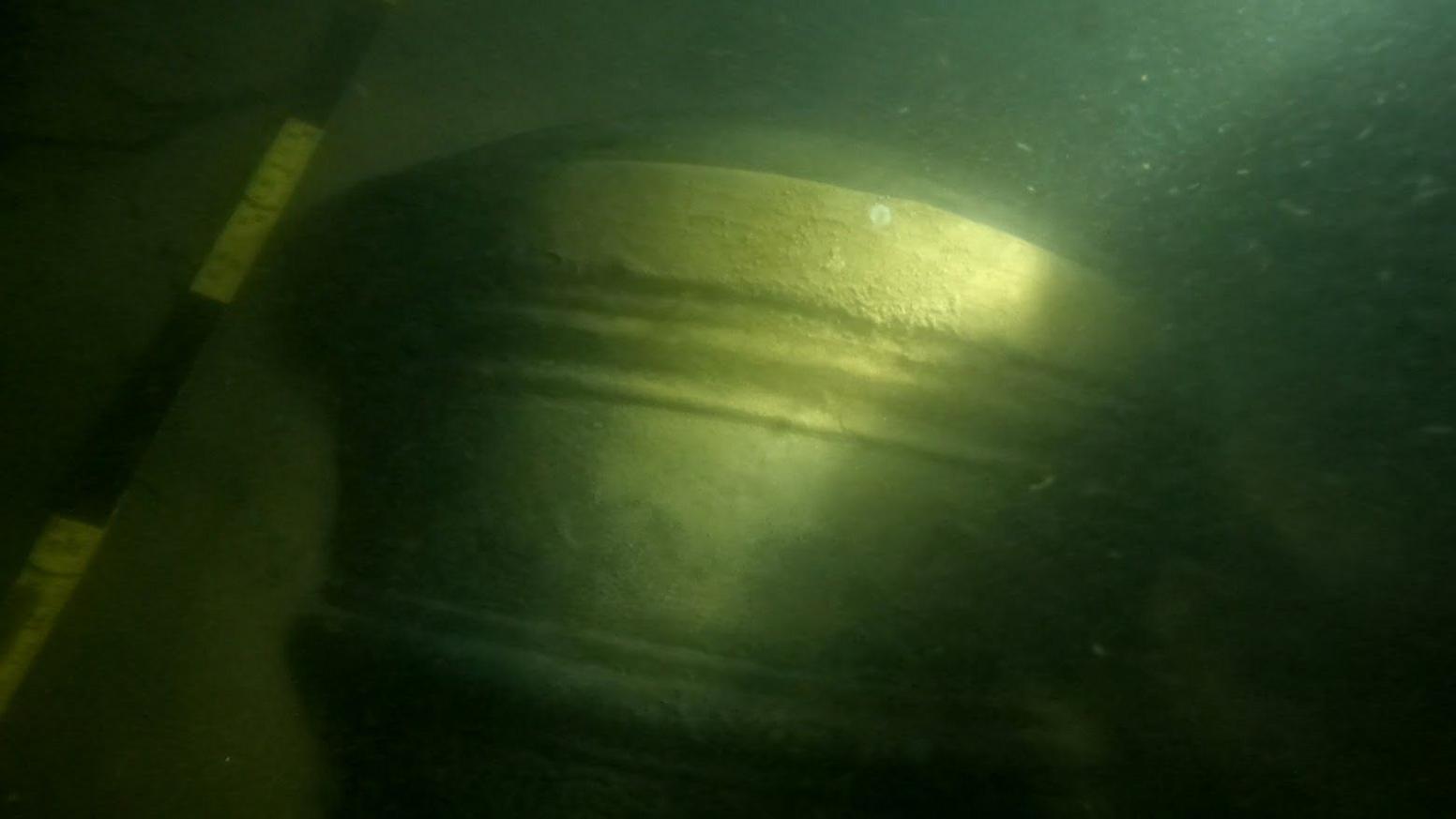 The barrel or shot end of a 17th Century gun or cannon appearing through the murky water of the Thames Estuary