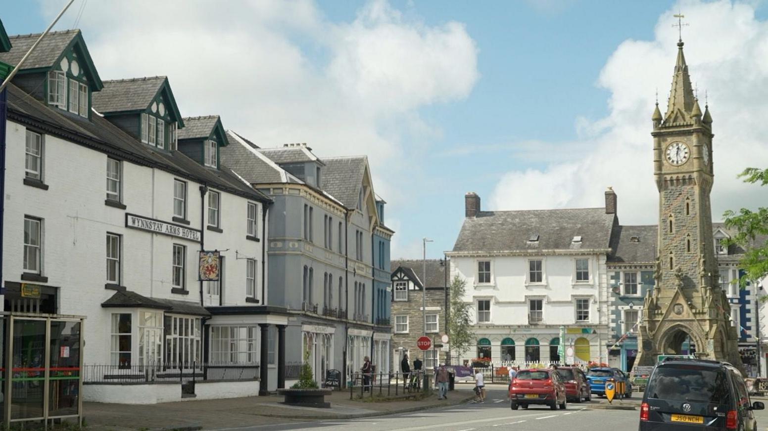 Canol tref Machynlleth sy'n dangos pa mor agor yw Gwesty'r Wynnstay, ar y chwith, i'r cloc, ar y dde