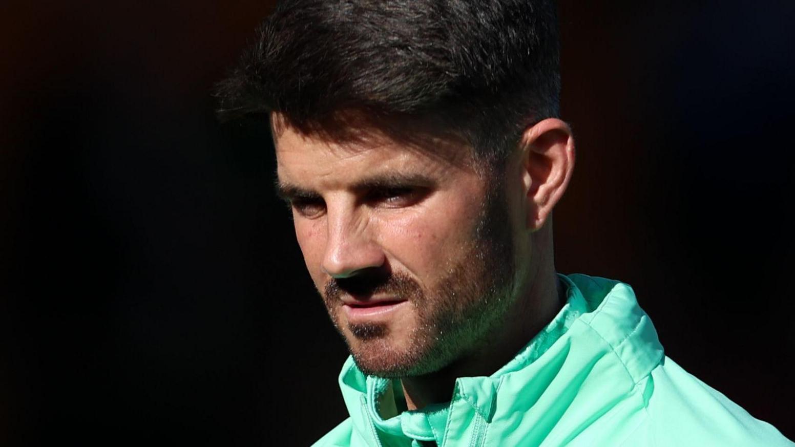 Martin Drury wearing a green jacket looks down