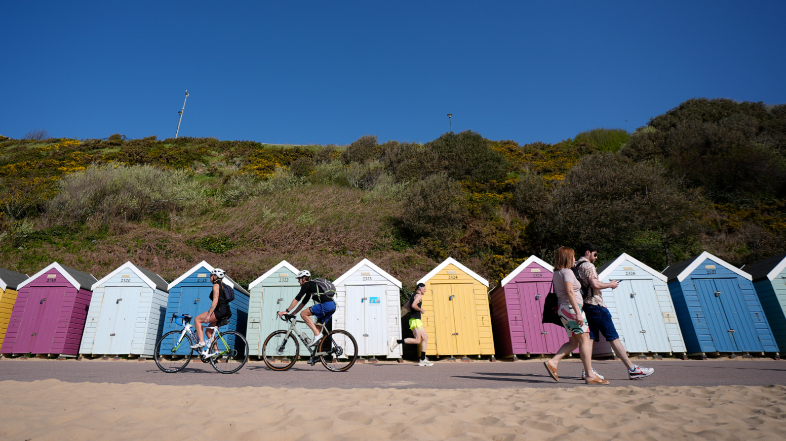 People make their way past beach huts on Bournemouth beach in Dorset.