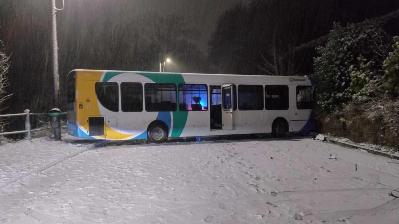 A bus is blocking a road. The road is covered in snow.