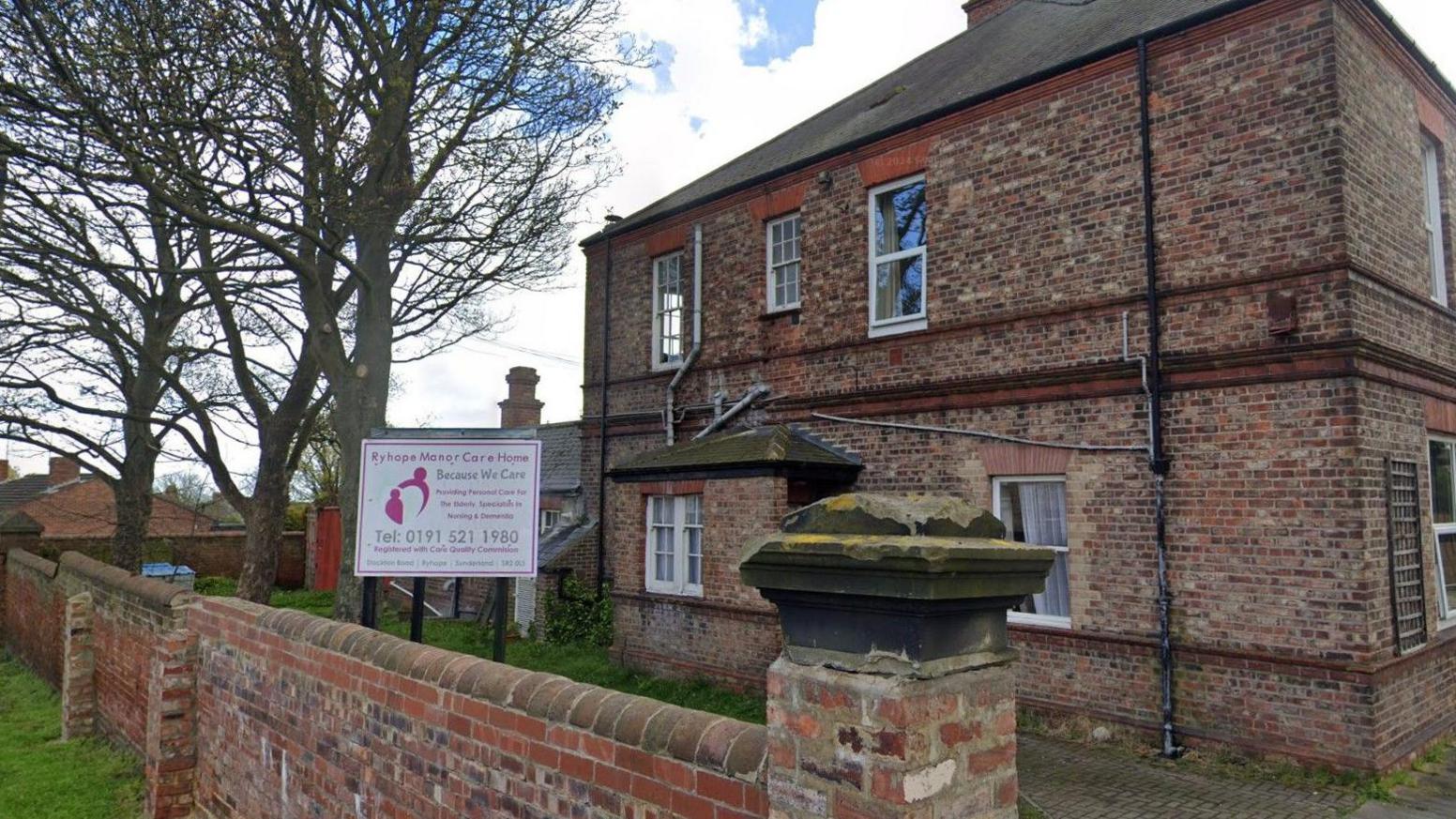 Brick building the size of a large house with trees on the grass outside as well as a sign that says "Ryhope Manor Care Home" in pink. 