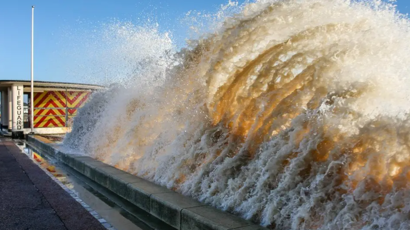 A large wave crashing against the promenade in Lowestoft.