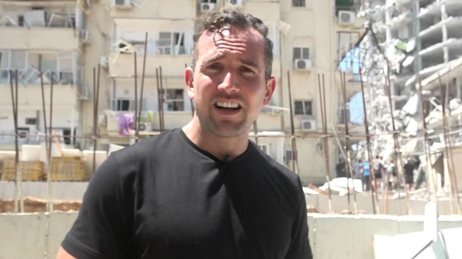 Hugo Bachega in front of a damaged building in Israel's Bat Yam