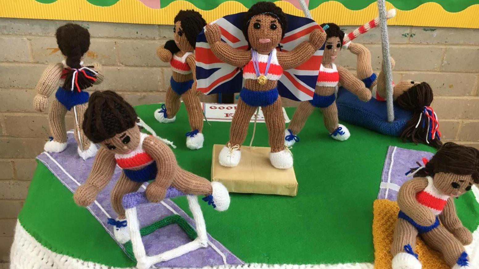 Knitted athletes, one of whom is jumping a hurdle