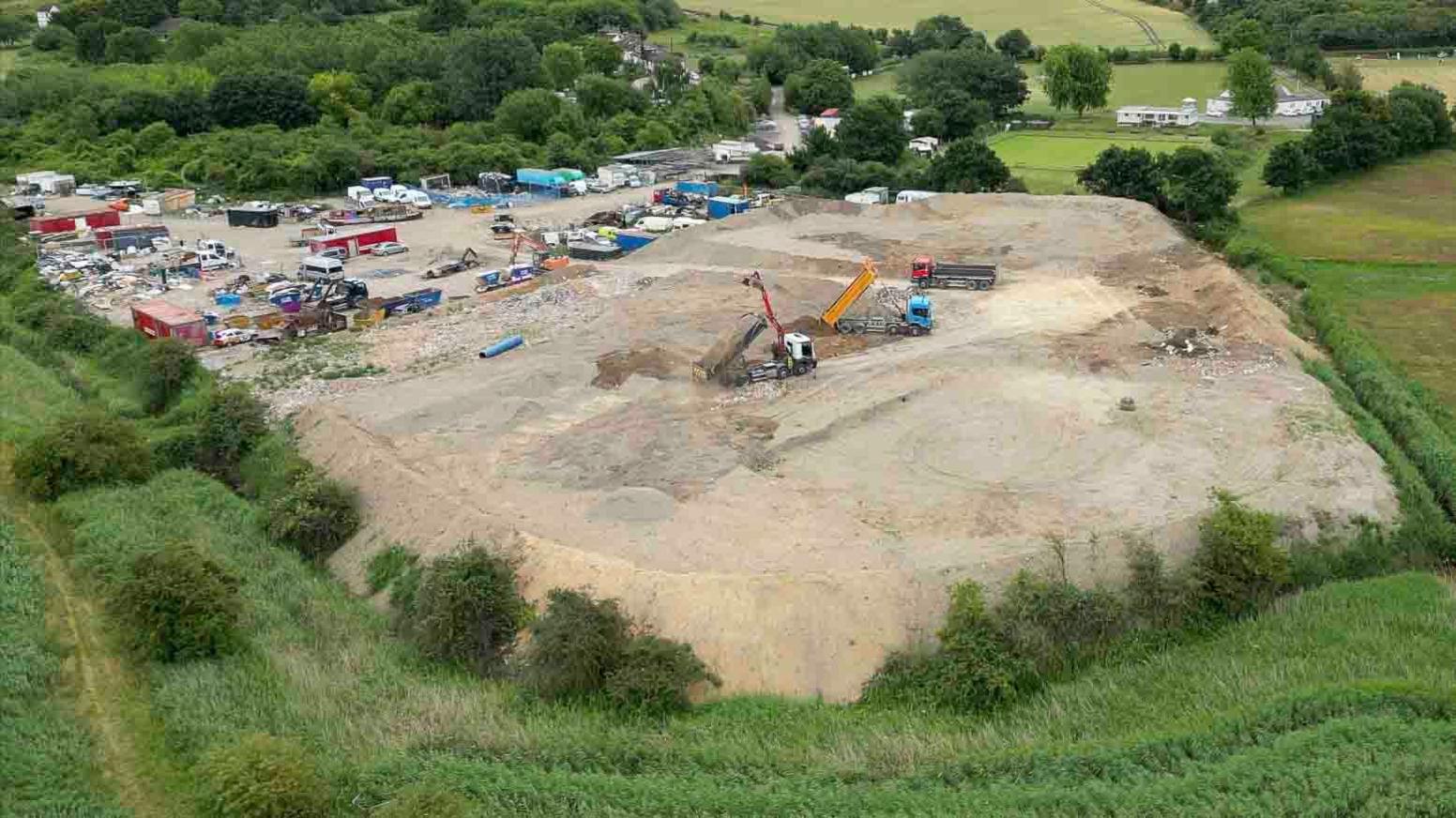 An aerial shot of lorries working on a brown patch of land