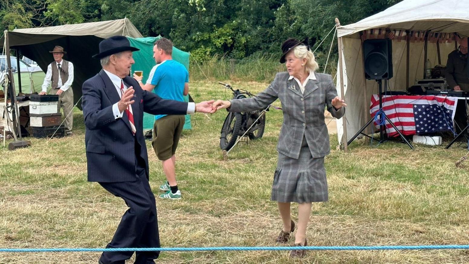 a older couple in traditional 40s wear dancing to the music.