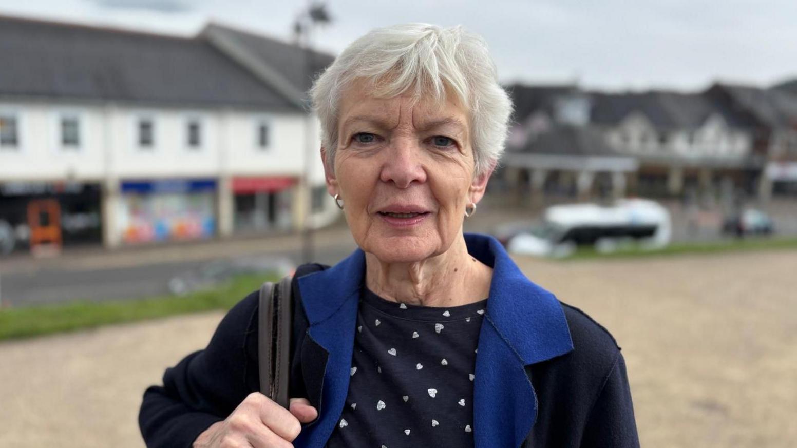 Ann Lewis yn sefyll y tu allan i gastell Caerffili.