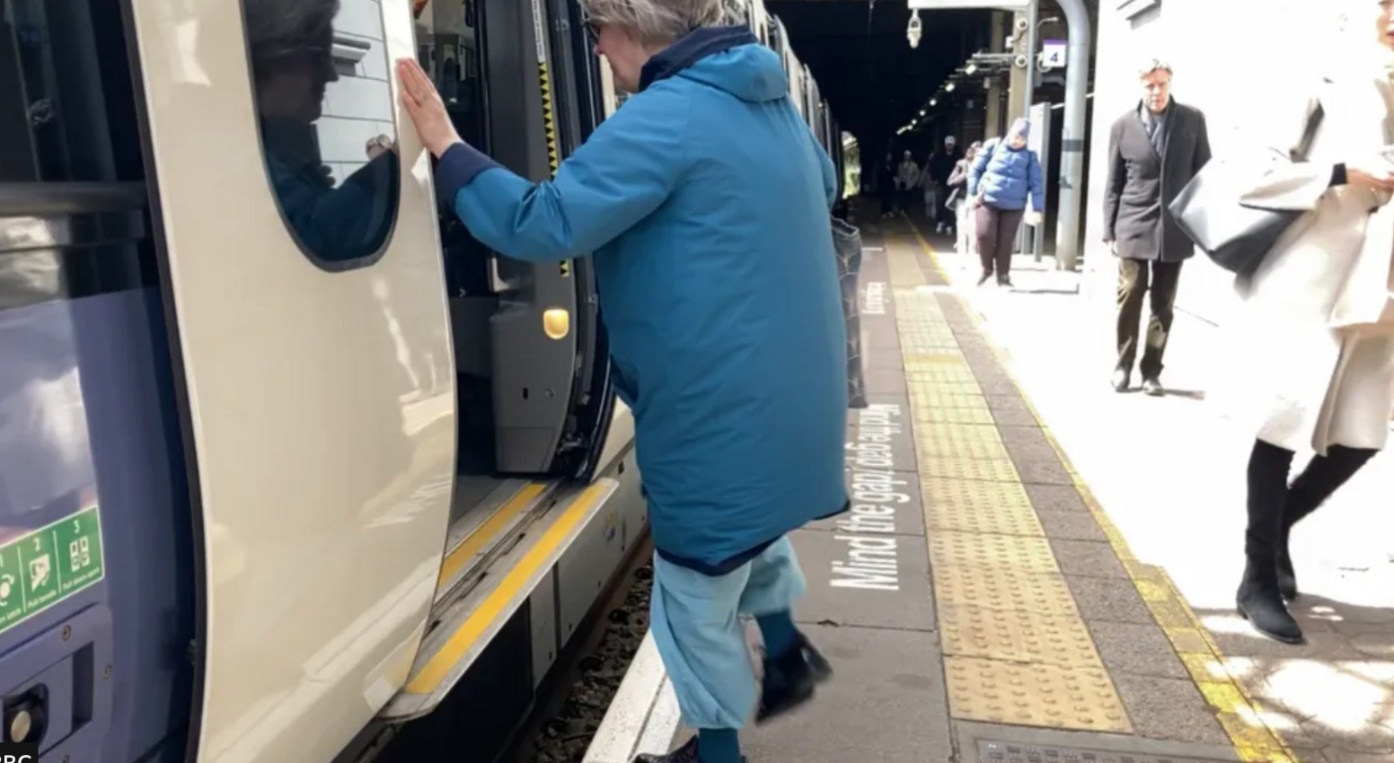 A woman navigating the gap to board a train at Ealing Broadway