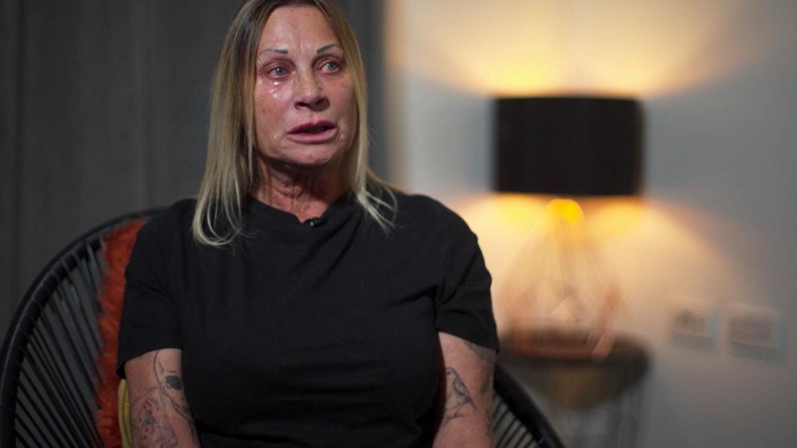 Tracey McCafferty, a middle-aged woman with shoulder-length blond hair, a black top and tattooed arms.