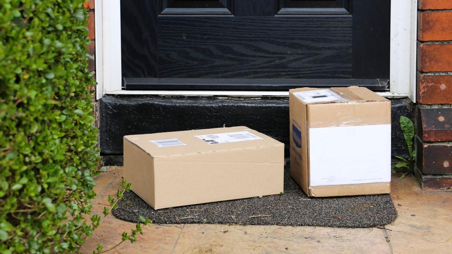 Two boxed parcels on a doorstep with a black door in the background