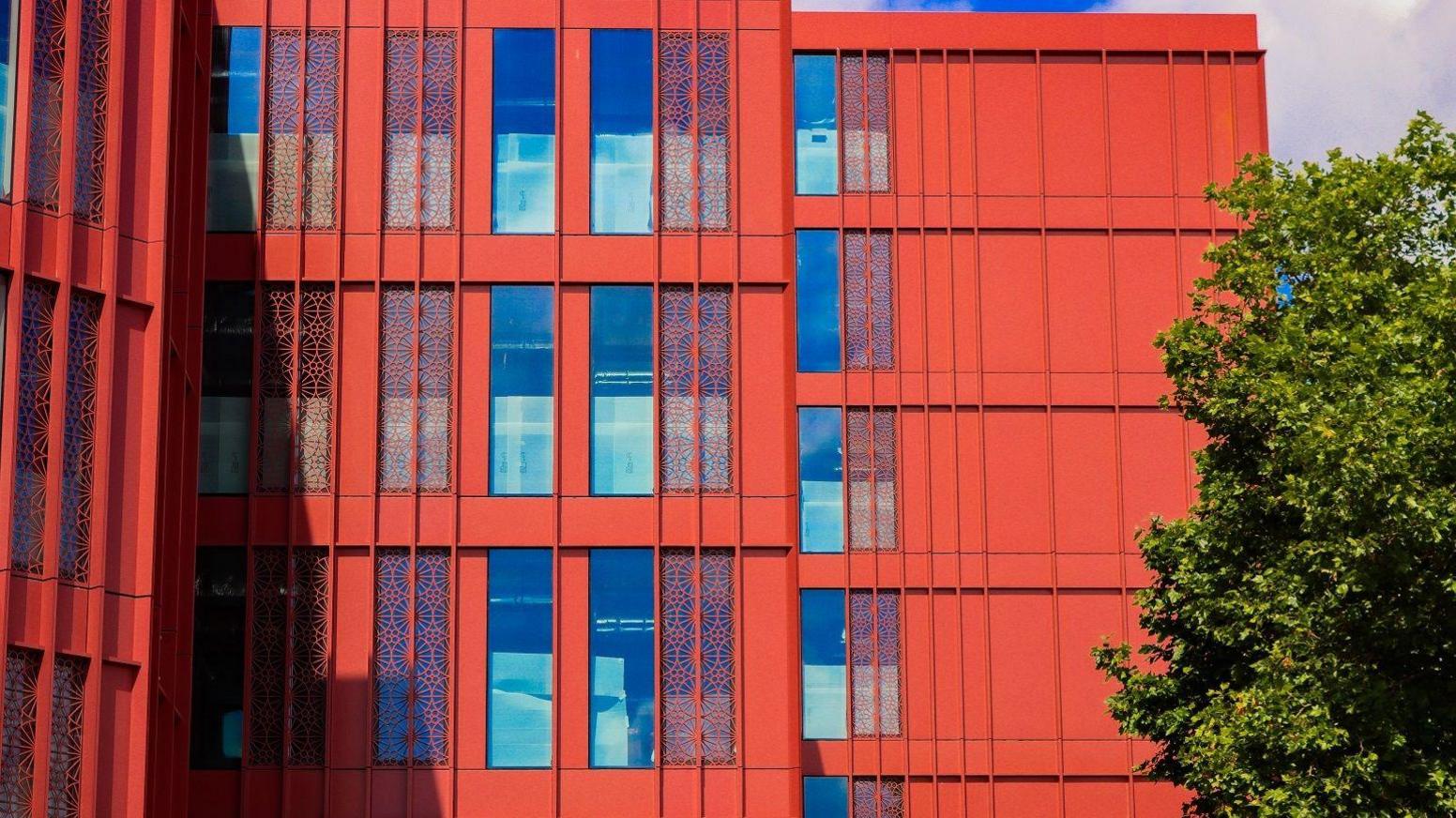 The side of the development, clearly showing the bright red panelling and the intricate red detailing over part of the windows. 