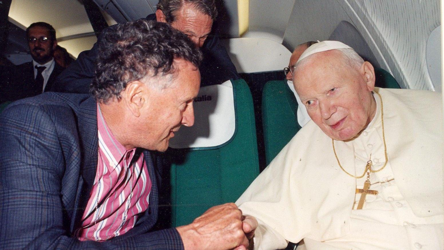 David Willey, wearing a suit and a pink shirt, talks with Pope John Paul II during a plane trip back to Rome from Bulgaria 26 May 2002