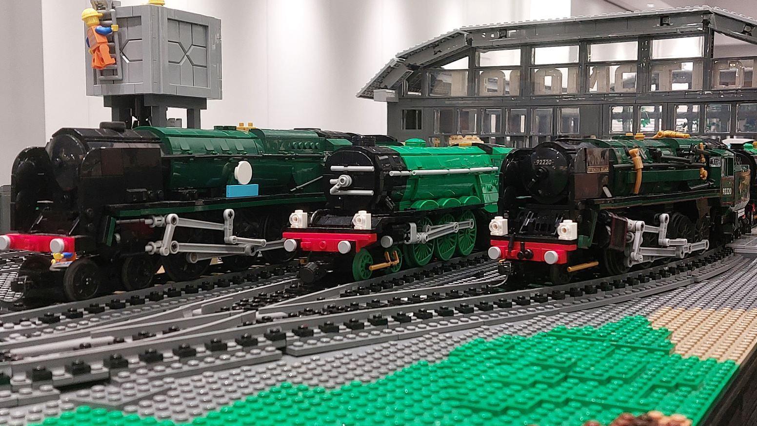 Three Lego locomotives on track - two black and one green